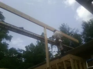 Carpenter setting a ridge beam over a new addition frame — Ice Dam Removal by Roofing Brothers in Cameron